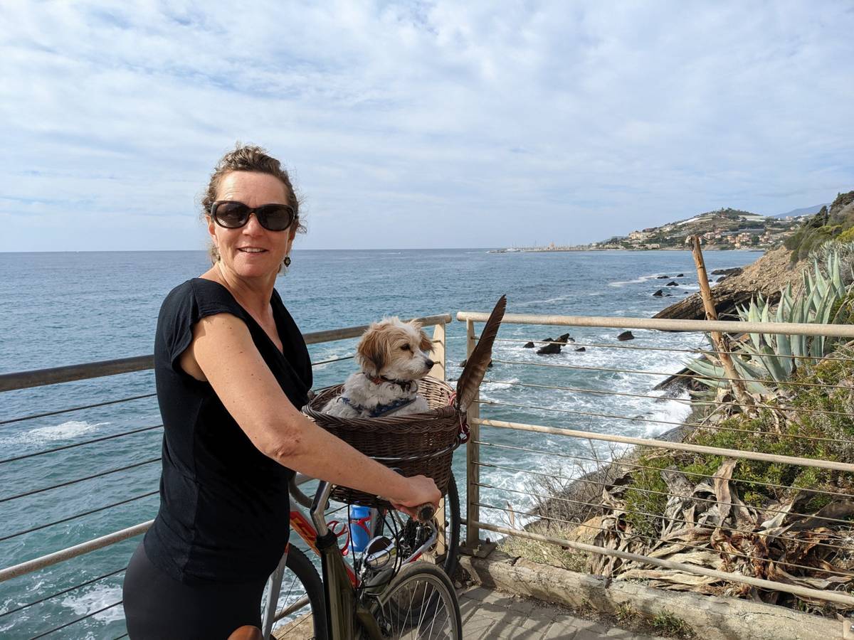 My wife with our dog Lillie in a bike basket at a coastal viewpoint near Cipressa