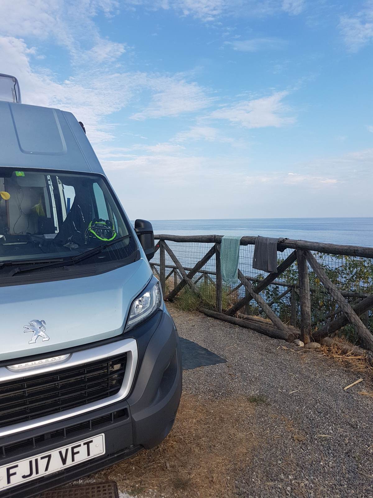 A Peugeot motorhome parked at a coastal viewpoint along the Ligurian coast near Imperia