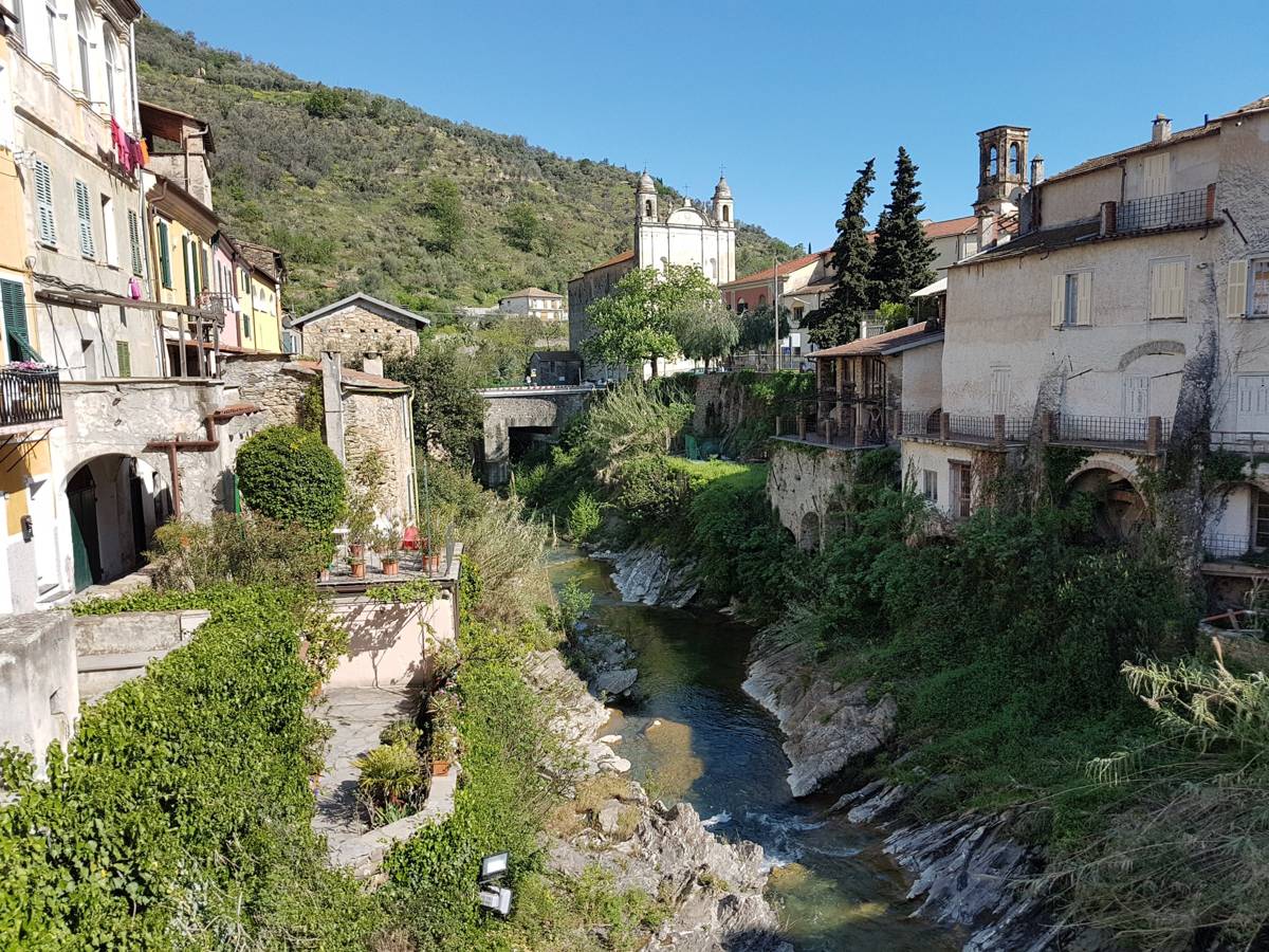 A narrow riverside street through a Ligurian hill village near Dolcedo