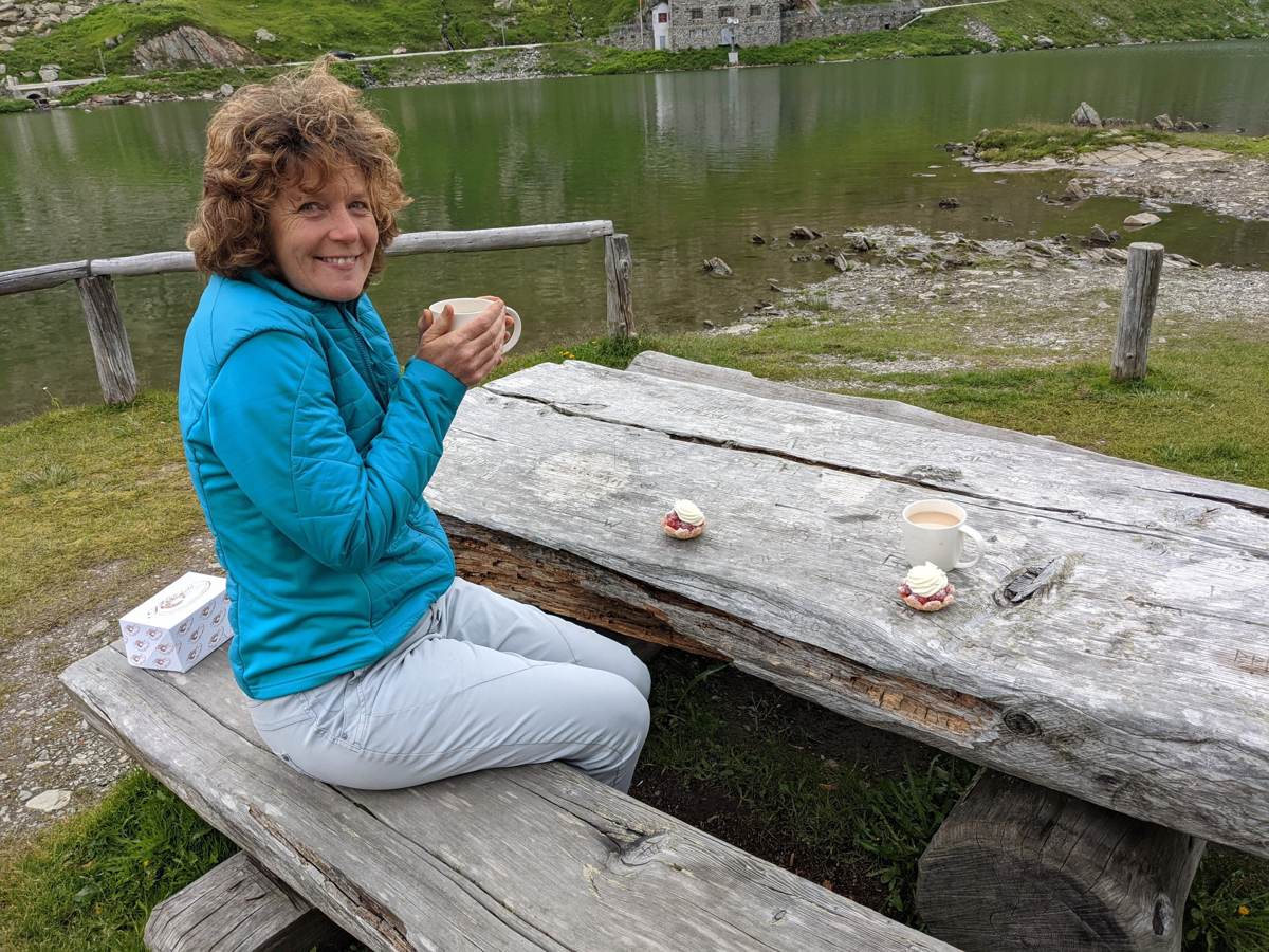 My wife at a picnic table by the summit lake at Grand St Bernard Pass