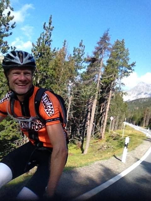 Me riding in an orange Mr Feelgood cycling jersey on the road up the Pass dal Fuorn, Switzerland