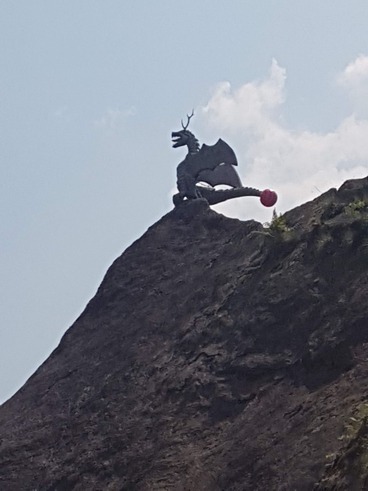 A metal dragon sculpture on a rocky summit above Brione, Verzasca Valley