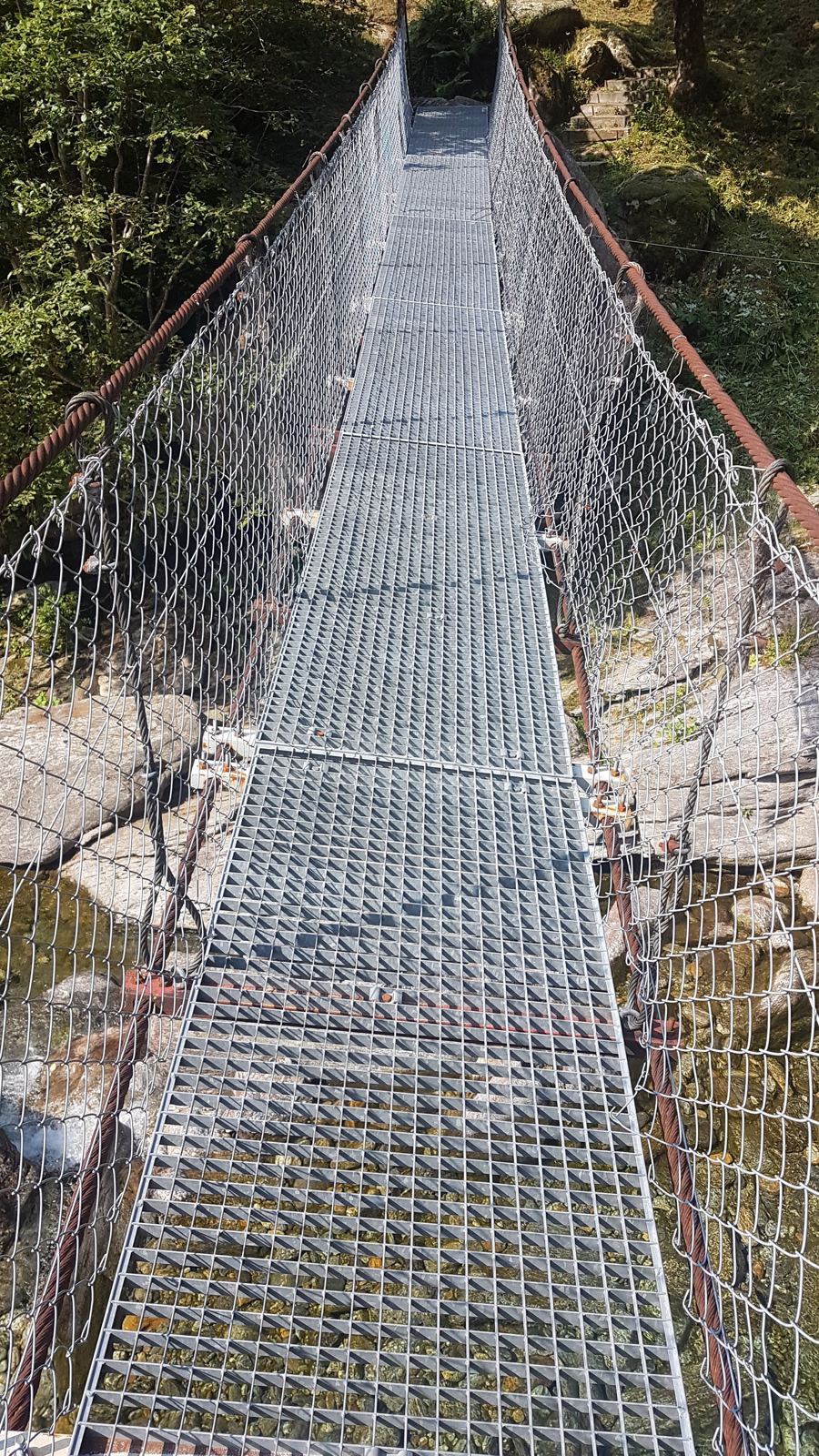 A steel suspension footbridge crossing the Verzasca river gorge
